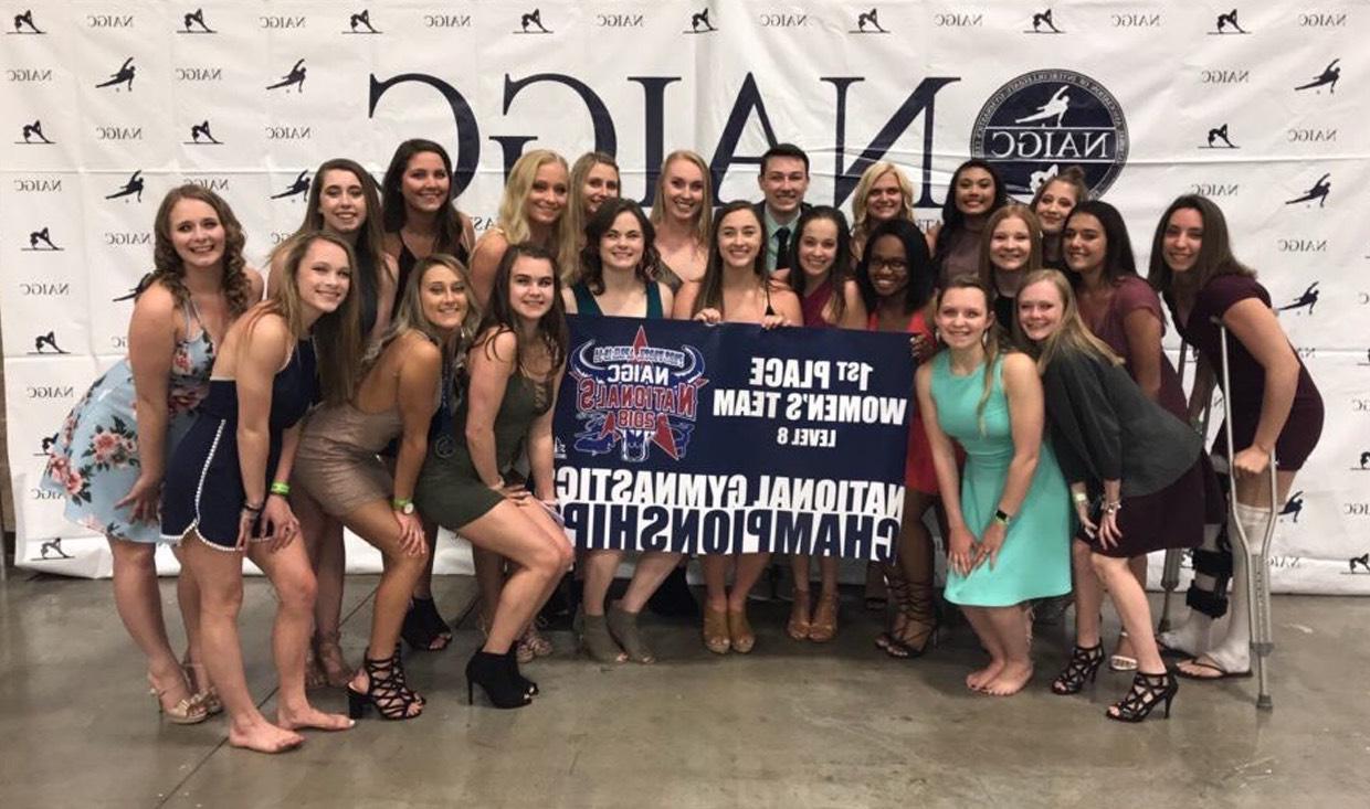 Gymnastics athletes pose with national championship banner at year-end banquet.